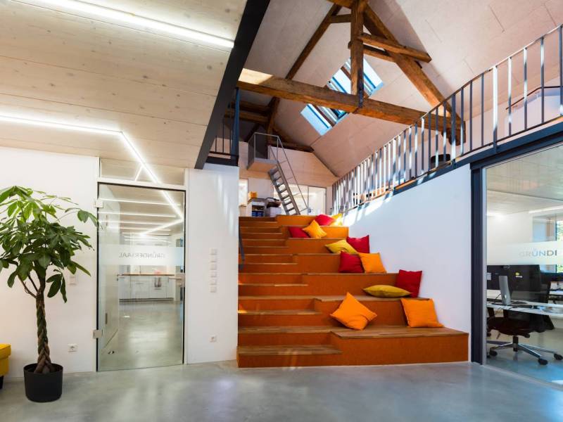 Helles Coworking-Space im Gründersaal Tübingen mit großer Sitztreppe, bunten Kissen und modernem Loft-Design.