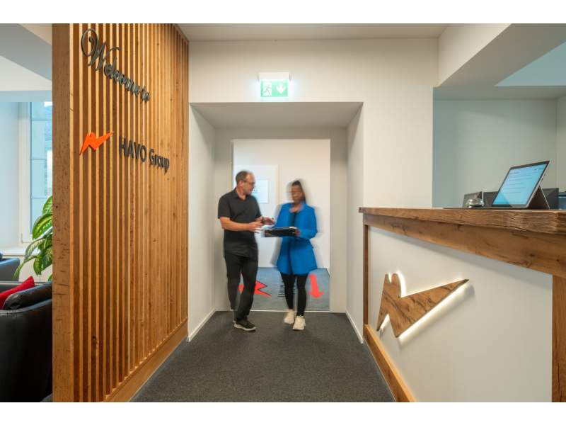 Moderner Empfangsbereich der HAVO Group AG mit Holzdetails und beleuchtetem Logo
