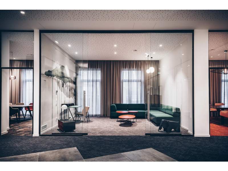 Goldbach Kirchner Schiebetürsystem aus Glas als transparente Abtrennung eines Lounge- und Besprechungsbereichs