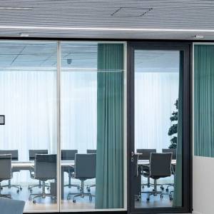Goldbach Kirchner Rohrrahmentür mit Aluminiumrahmen und Glasfüllung als Zugang zu einem verglasten Besprechungsraum