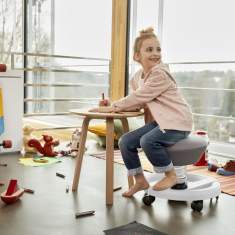 Kind nutzt Aeris Swoppster Drehstuhl am Tisch für ergonomisches Arbeiten