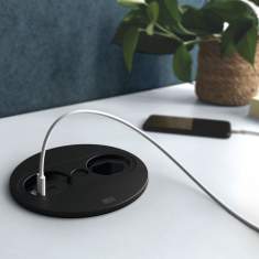 Runde Einbausteckdose BACHMANN TWIST 2 in Schwarz, mit USB-Anschluss und Stromversorgung, eingebaut in einer weißen Tischplatte