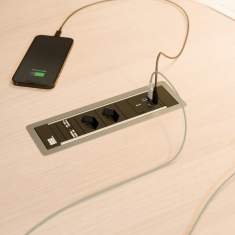 Integrierter Bachmann USB-C Next Generation Charger in einer Tischanschlusslösung – zwei Geräte werden parallel über moderne USB-Anschlüsse aufgeladen, ideal für schnelles und effizientes Laden im Büroalltag
