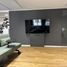 Besprechungsbereich im Satellite Office Ludwigpalais mit grünem Sofa, integriertem Tisch und großem Flachbildschirm