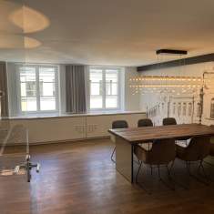 Helles Besprechungszimmer im Satellite Office Ludwigpalais mit großem Holztisch, Designerstühlen und moderner Pendelleuchte
