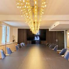 Großer Konferenzraum im Satellite Office Ludwigpalais mit langem dunklen Tisch, blauen Stühlen und eleganter goldener Pendelleuchte