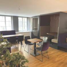 Moderne Coworking-Lounge im Satellite Office Ludwigpalais mit Sitznischen, Holztischen, schwarzen Stühlen und Tageslicht