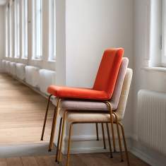 Skandiform Bolero Stühle stapelbar – Varianten in Orange, Beige und gemusterter Polsterung mit ockerfarbenem Gestell.