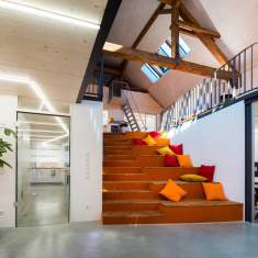 Helles Coworking-Space im Gründersaal Tübingen mit großer Sitztreppe, bunten Kissen und modernem Loft-Design.