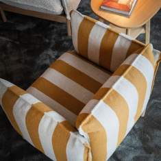 NC Nordic Care Cirrus Loungesessel mit gestreiftem Bezug neben Beistelltisch im Wohnbereich