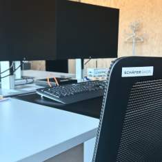 Moderner Bildschirmarbeitsplatz mit ergonomischer Büroeinrichtung im Neubau von Hug Baustoffe