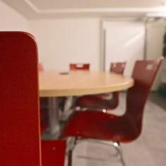 Kompakter Besprechungsbereich mit roten Besucherstühlen und rundem Konferenztisch