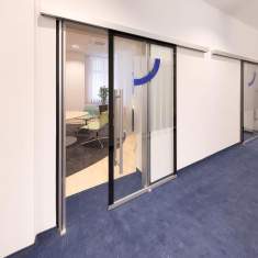 Goldbach Kirchner Ganzglas-Schallschutz-Schiebetür mit sichtbarer Laufschiene vor einem Besprechungsraum