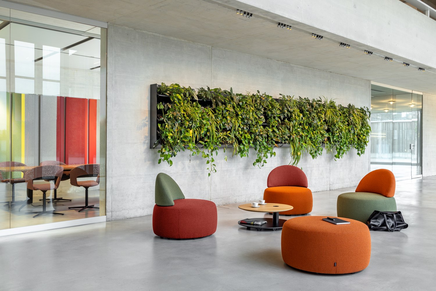 Nachhaltige Sitzmöbel InCycle von Girsberger in modernem Büroambiente mit vertikalem Pflanzenelement.